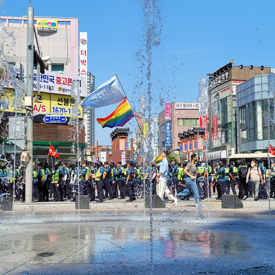 대구퀴어문화축제가 열리는 17일 오전 주최 측의 대중교통전용지구 도로 사용 여부를 놓고 경찰과 행정 당국이 충돌하는 가운데 행사 참가자가 무지개 깃발을 들고 걸어가고 있다.  연합뉴스